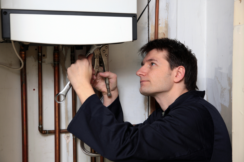 close up image of engineer fixing boiler underneath