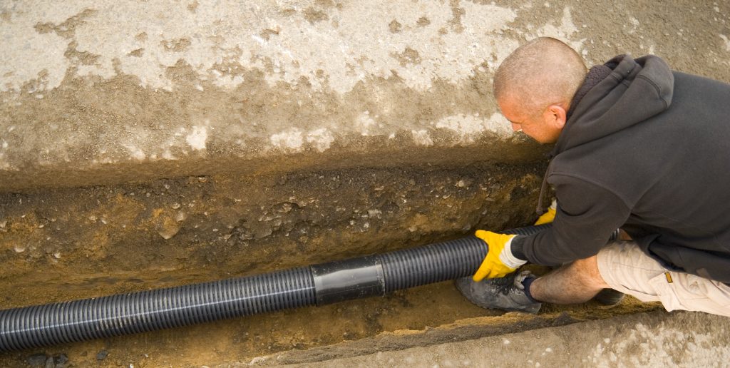 Shot of a road worker fitting drain pipes in a drainage ditch 